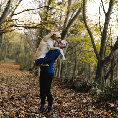 woman-carrying-dog-while-standing-in-the-middle-of-the-1612861
